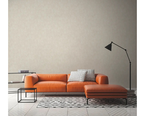 Woonkamer met oranje bank, voetenbank, lamp en vloerkleed op een lichte houten vloer