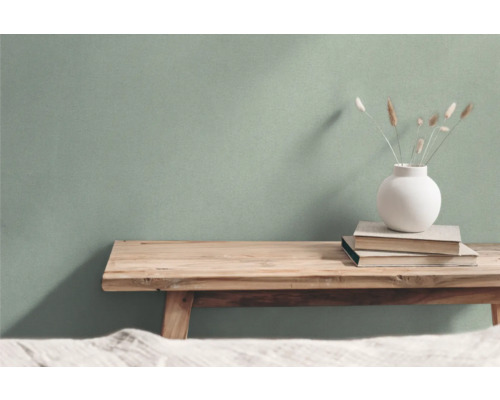 Woonkamer setting met houten bank, boeken en vaas voor een muur