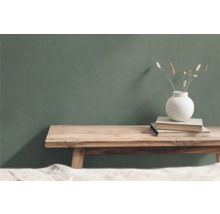 Decoratieve scène met houten tafel, boeken en vaas voor een groene wand