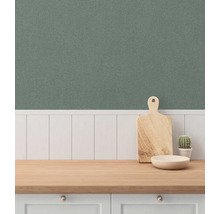 Keukenscène met houten snijplank, schaal en cactus op een aanrecht tegen een groene wandbekleding.