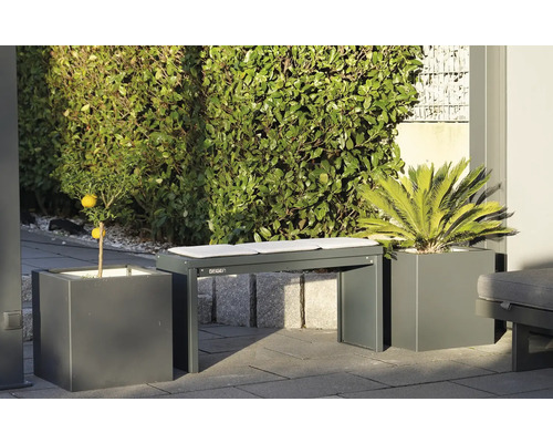 Tuinbank met kussens tussen plantenbakken met sierplanten