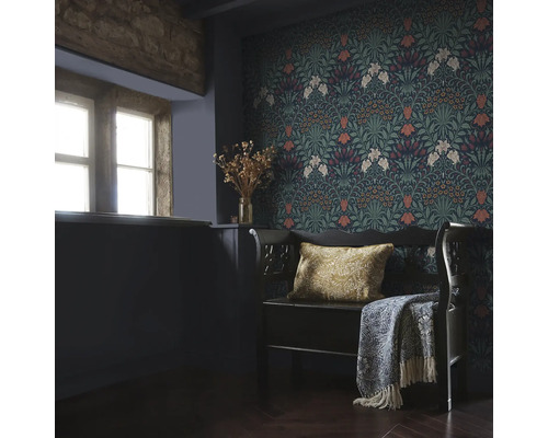 Inrichtingsvoorbeeld met bloemmotief behang, bank met kussen en sprei in een kamer met raam