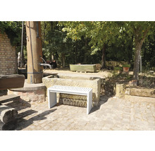 Tuinaanzicht met stenen fontein en een witte bank