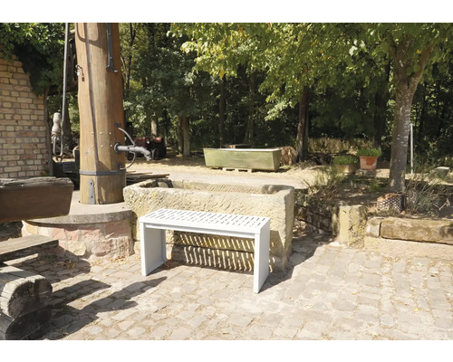 Tuinaanzicht met stenen fontein en een witte bank