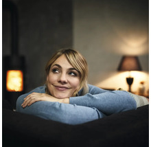 Vrouw ontspant op de bank met een houtkachel op de achtergrond