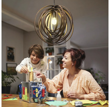 Een moeder knutselt met haar kind onder een decoratieve hanglamp.