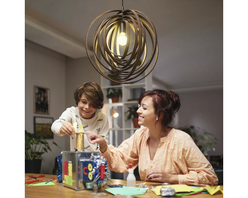 Een moeder knutselt met haar kind onder een decoratieve hanglamp.