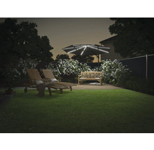 Tuin met ligstoelen, bank en verlichte parasol in de schemering