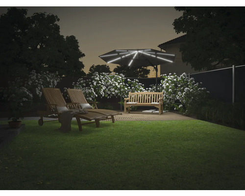 Tuin met ligstoelen, bank en verlichte parasol in de schemering