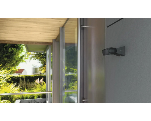 Buitenlamp aan een huismuur met uitzicht op de tuin