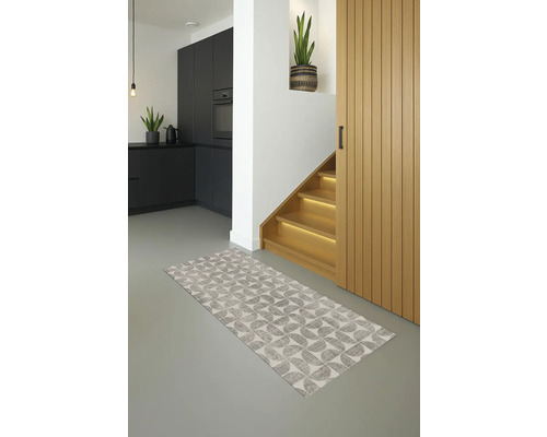 Interieurfoto van een modern ingerichte hal met een patroonteppich, een trap, een houten deur en een deel van een kitchenette.