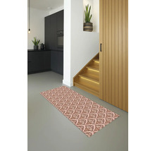 Een vloerkleed met motief ligt in een lichte hal met trap en keuken.