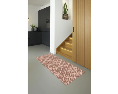 Een vloerkleed met motief ligt in een lichte hal met trap en keuken.