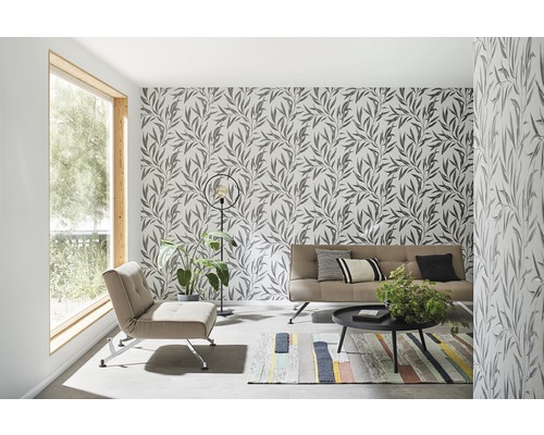 Woonkamer met bloemenbehang, fauteuil, bank, tafel en vloerkleed.