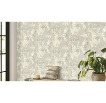 Woonkamer met een behang met plantenmotief, een kussen, een hoed en een kamerplant.