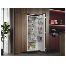 Geïntegreerde koelkast met open deur en levensmiddelen in een moderne keuken.