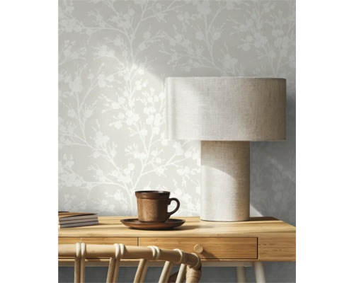 Interieurscène met een gestructureerd bloemenbehang, een tafel met een lamp en een kop