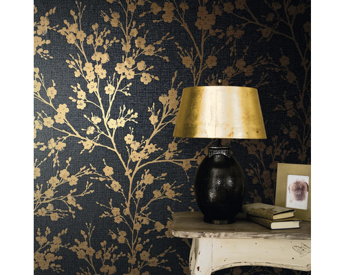 Close-up van een muur met donkerblauw bloemenbehang met een tafel, een lamp, boeken en een fotolijst