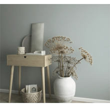 Decoratieve scène met een houten commode, een vaas met gedroogde bloemen en een selectie woonaccessoires.