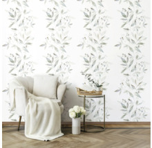 Woonkamer met fauteuil, bijzettafel en behang met bladerenmotief.