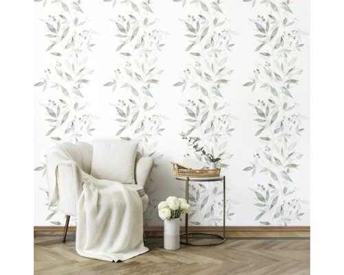 Woonkamer met fauteuil, bijzettafel en behang met bladerenmotief.