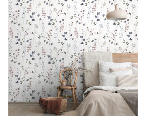 Slaapkamer met bloemetjesbehang, bed en rotan stoel