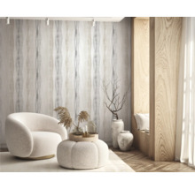 Woonkamer met fauteuil, hocker, behang en houten lambrisering voor een lichte sfeer.