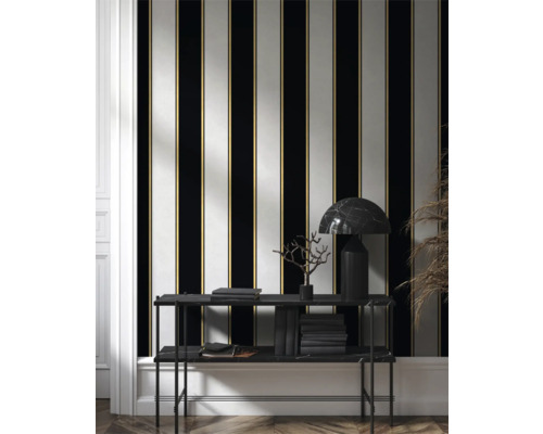 Kamerweergave met gestreepte behang in zwart, wit en goud, evenals een plank met boeken en een lamp.