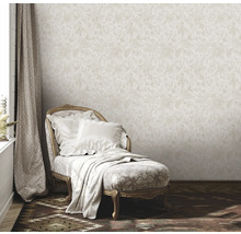 Scene met beige bloemenbehang, ligstoel met kussens en deken, en gordijn