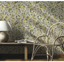 Decoratieve kamer met een behang met citroenen en olijftakken, een houten tafel, een lamp, een boek en een rotan stoel.