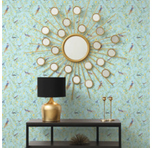 Decoratief interieur met een ronde spiegel in de vorm van een zon, een tafellamp en een console tegen een patroonbehang.