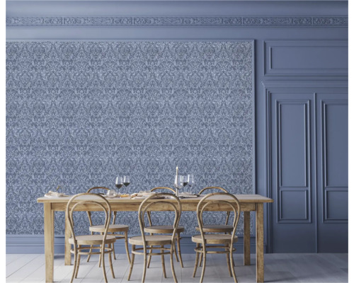 Eetkamer met sierlijk behang, houten tafel en stoelen.