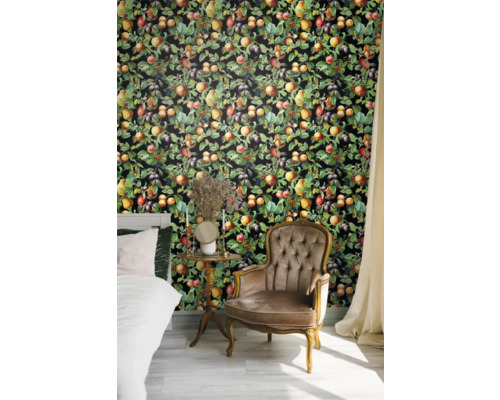 Slaapkamer met bed, fauteuil en wandbekleding met fruitmotieven.