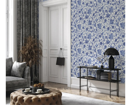 Woonkamer met bloemetjesbehang, bank, kruk en decoraties voor een gezellige sfeer