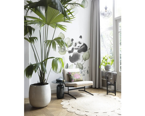 Woonkamer met palmboom in pot, fauteuil, tapijt en muursticker