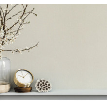 Lichte wand met decoratieve elementen zoals een bloemenvaas, een klok en een plantenstuk