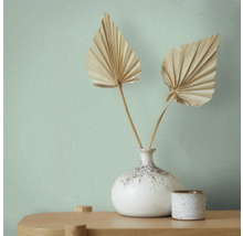 Behang met textielpatroon, vaas met waaierbladeren op een tafel