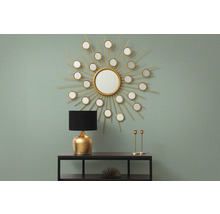 Decoratief interieur met spiegel in de vorm van een zon, lamp en kandelaars op een plank.