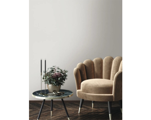 Decoratieve scène met fauteuil, bijzettafel, kandelaars en bloemenvaas in een stijlvolle ambiance.