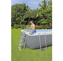 Man gebruikt een ladder om in een rechthoekig zwembad in de tuin te klimmen