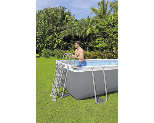 Man gebruikt een ladder om in een rechthoekig zwembad in de tuin te klimmen