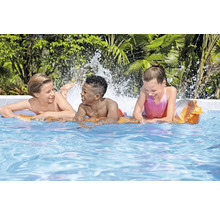 Drie kinderen spelen in het zwembad met waterspetters.