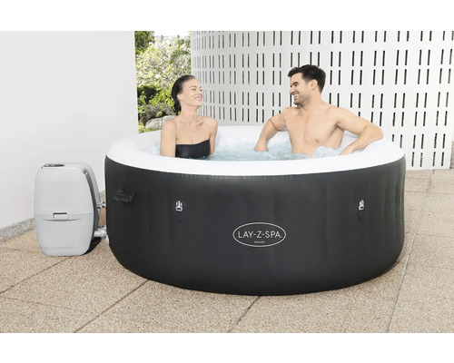 Opblaasbare Lay-Z-Spa Miami whirlpool met twee personen in het water en een bijbehorende pomp.