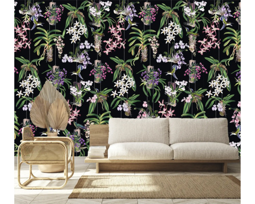 Kamerweergave met een behang met orchideeën en kolibriemotief achter een bank, een fauteuil en een gedroogde palm.