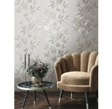 Decoratieve muur met bladerpatroon, fauteuil en bijzettafel in de woonkamer.