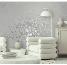 Gedecoreerde kamer met behang met bloemmotief, fauteuil en staande lamp.