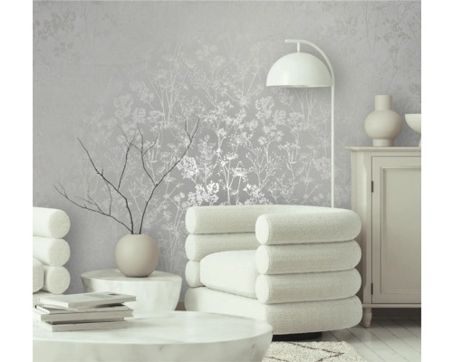 Gedecoreerde kamer met behang met bloemmotief, fauteuil en staande lamp.