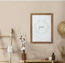 Decoratieve wanddecoratie met het woord vrijheid in een houten frame, gecombineerd met decoratieve elementen zoals een ladder, een katoenplant, een hoed en vazen op een tafel.