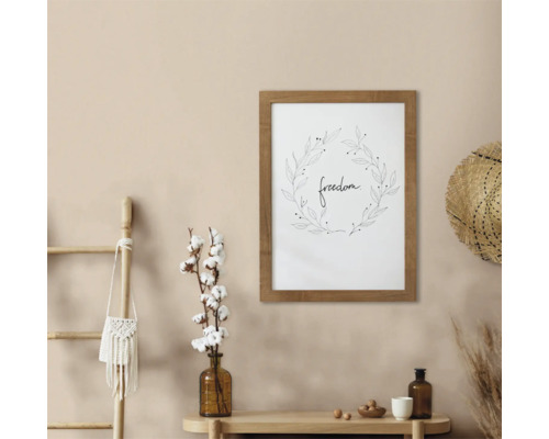 Decoratieve wanddecoratie met het woord vrijheid in een houten frame, gecombineerd met decoratieve elementen zoals een ladder, een katoenplant, een hoed en vazen op een tafel.