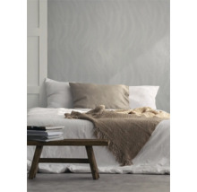 Slaapkamer met bed, sprei, kussens, stapel boeken en behang met golfpatroon